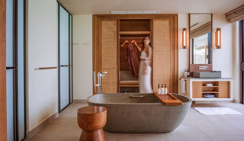 Sunrise Water Villa with Private Pool Modern tropical bathroom suite with a natural stone soaking tub, minimalist vanity, and integrated dressing area in a luxury overwater villa at Kuda Villingili Resort Maldives by Kenwood Travel