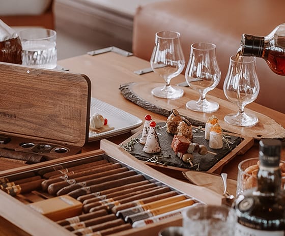 Cigar Lounge Luxury cigar lounge amenities featuring a humidor of hand-rolled cigars, a whiskey tasting set, and artisanal appetizers in a high-end resort setting at Kuda Villingili Resort Maldives by Kenwood Travel