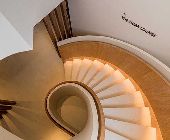 Cigar Lounge Top-down view of a modern white spiral staircase with light wood accents and integrated LED lightin at Kuda Villingili Resort Maldives by Kenwood Travel