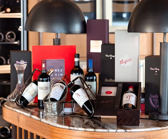 Cigar Lounge Close-up of a high-end wine cellar display featuring vintage bottles, branded gift sets, and a marble counter in a luxury resort or private club setting at Kuda Villingili Resort Maldives by Kenwood Travel