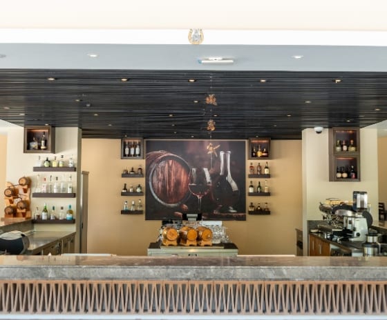 The Bar bar area featuring a marble countertop, terracotta textured base, and shelves stocked with premium spirits and wine at Kuda Villingili Resort Maldives by Kenwood Travel