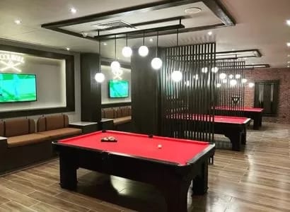 Billiard Bar Spacious game room with red felt billiard tables, comfortable booth seating, and hanging globe lights at Baron Resort Sharm El Sheikh by Kenwood Travel