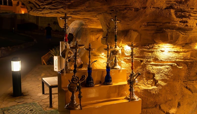Cave Bar Traditional shisha pipes arranged on display steps inside a dimly lit stone cave lounge at night at Royal Savoy Sharm El Sheikh by Kenwood Travel