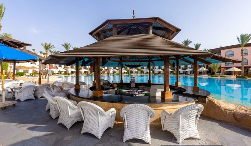 Rocky Pool Bar circular wooden poolside bar with white wicker chairs next to a large blue resort swimming pool at Royal Savoy Sharm El Sheikh by Kenwood Travel