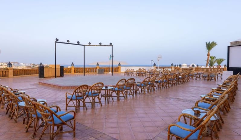 Le Balcony Outdoor resort terrace with wicker chairs and an open-air stage overlooking the ocean at Royal Savoy Sharm El Sheikh by Kenwood Travel