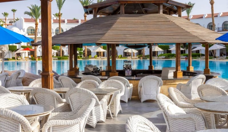 Rocky Pool Bar circular wooden poolside bar with white wicker chairs next to a large blue resort swimming pool at Royal Savoy Sharm El Sheikh by Kenwood Travel
