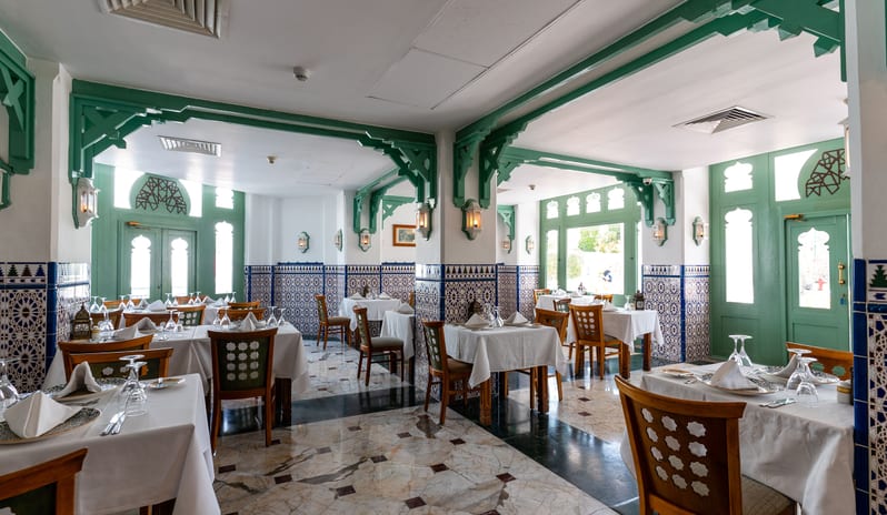 Egyptian Restaurant dining room with marble flooring, white tablecloths, crystal glassware, and Mediterranean-inspired green woodwork design at Baron Resort Sharm El Sheikh by Kenwood Travel