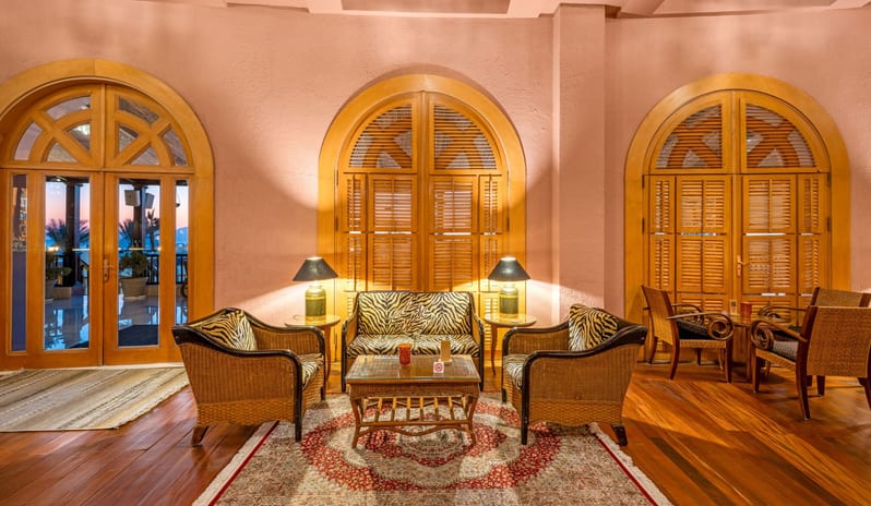 Safari circular lounge area featuring wicker furniture with zebra-print cushions, a traditional patterned rug, and large arched wooden shutter windowsat Royal Savoy Sharm El Sheikh by Kenwood Travel