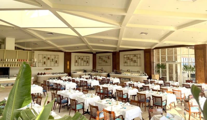 Sinai Restaurant showing the elegant indoor setup, buffet service stations in the background, and large windows bringing in natural light at Baron Resort Sharm El Sheikh by Kenwood Travel