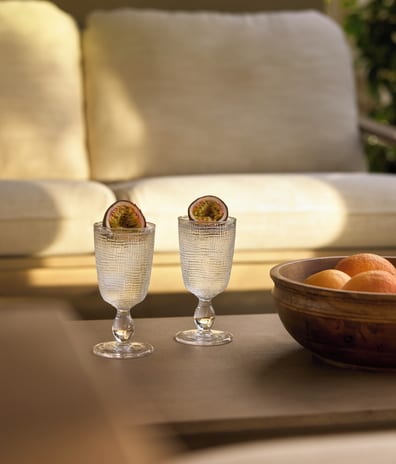 Deluxe Double Room Private Garden Sea View wooden bowl with oranges is beside them, with a sunlit outdoor resort lounge couch blurred in the background at Sani Club by Kenwood Travel