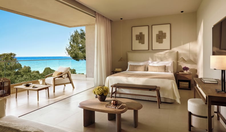 Junior Suite Grand Balcony Sea View Modern oceanfront bedroom with a balcony, neutral tones, and elegant wood furniture at Sani Club by Kenwood Travel