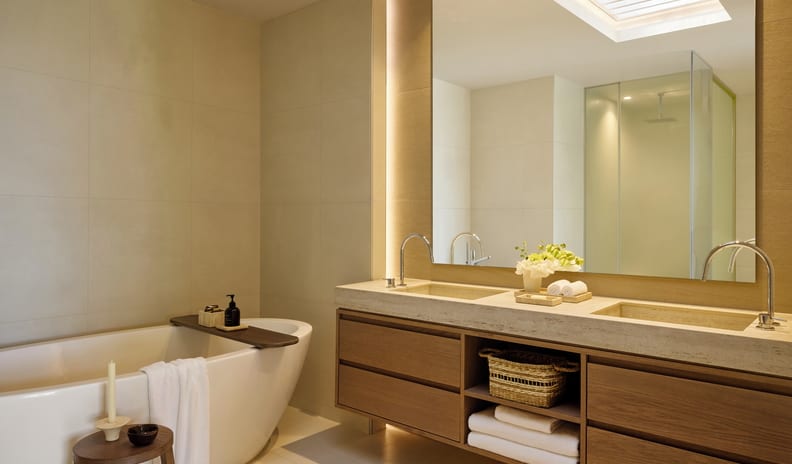 One Bedroom Bungalow Suite Private Pool Garden View bathroom suite featuring a double sink vanity, large mirror, rolled towels, and a white soaking tub in a warm neutral setting at Sani Club by Kenwood Travel