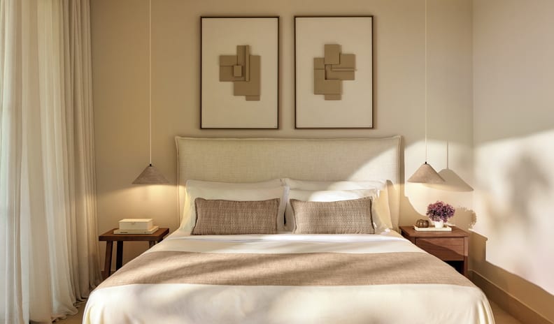 Family Suite Grand Balcony Sea View A minimalist hotel bedroom with a Japandi design, featuring a bed with neutral linens, two framed abstract 3D wall artworks, wooden nightstands, and hanging conical pendant lights. at Sani Club by Kenwood Travel