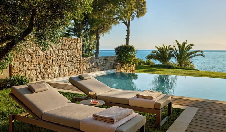 One Bedroom Bungalow Suite Private Pool Sea View Luxury resort infinity pool overlooking the ocean, featuring two premium lounge chairs on a wooden deck surrounded by lush grass at Sani Club by Kenwood Travel