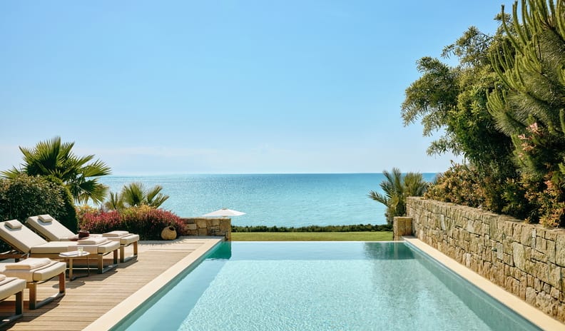 Two Bedroom Bungalow Suite PrIvate Pool Beach Front Modern Mediterranean pool deck design featuring natural stone walls, premium wooden decking, and lush coastal landscaping at Sani Club by Kenwood Travel