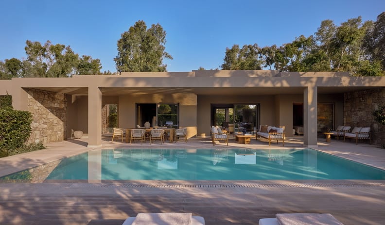 Three Bedroom Grand Residence Private Pool Garden View Exclusive private vacation villa showcasing a sunlit swimming pool with poolside lounge chairs, an al fresco dining setup, and lush surrounding trees at Sani Asterias by Kenwood Travel
