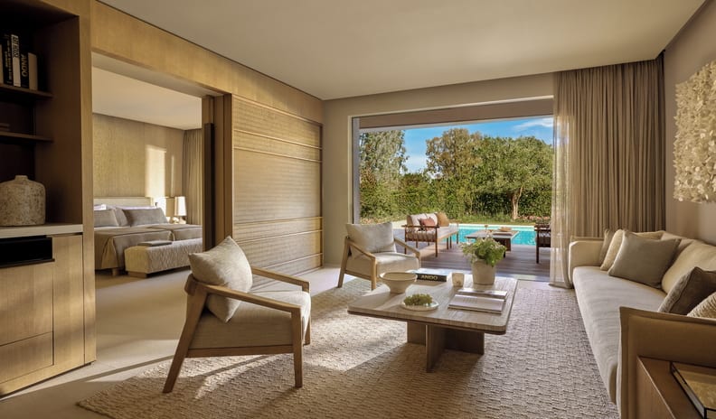 Three Bedroom Villa Pr. Pool Garden View Spacious master suite of a luxury resort villa, featuring an integrated living room, adjoining bedroom, and a direct view of a private poolside deck surrounded by lush gardens at Sani Asterias by Kenwood Travel