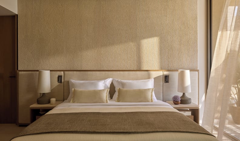 Three Bedroom Villa Pr. Pool Garden View king bed dressed in premium earth-toned linens, illuminated by soft natural sunlight next to a floor-to-ceiling glass balcony window at Sani Asterias by Kenwood Travel