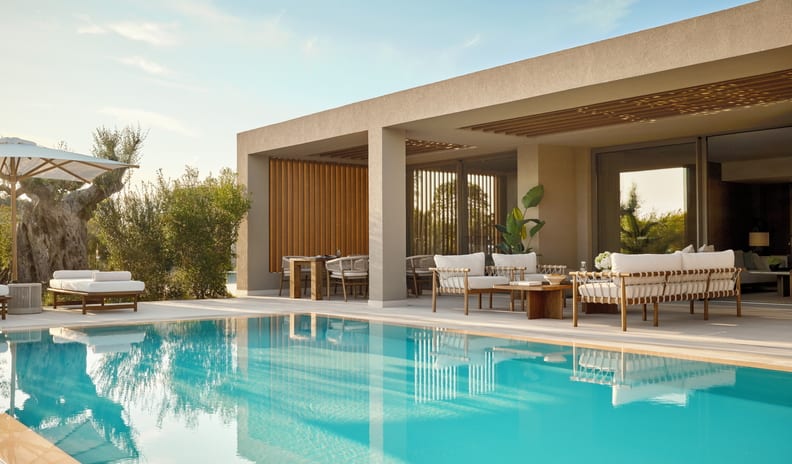 Three Bedroom Villa Pr. Pool Garden View villa exterior featuring a private swimming pool, sun loungers with white umbrellas, and an elegant outdoor terrace for relaxation and al fresco dining at Sani Asterias by Kenwood Travel
