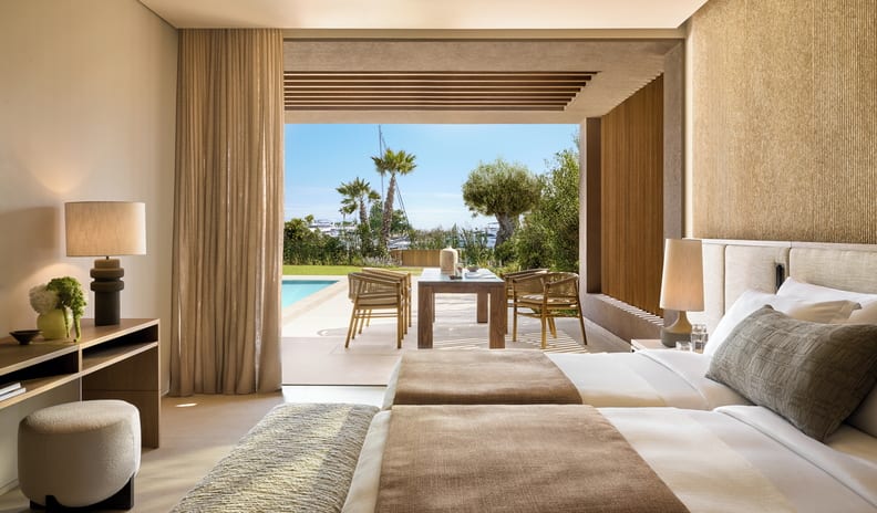 Three Bedroom Villa Pr. Pool Marina View twin bedroom with earth-toned decor, opening onto a private covered patio with an outdoor wooden dining table, swimming pool, and tropical landscaping at Sani Asterias  by Kenwood Travel