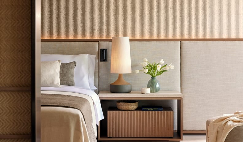Two Bedroom Residence Pr. Pool Beach Front SV bedside table with a modern table lamp, fresh white tulips in a vase, and a fluted wooden drawer at Sani Asterias by Kenwood Travel