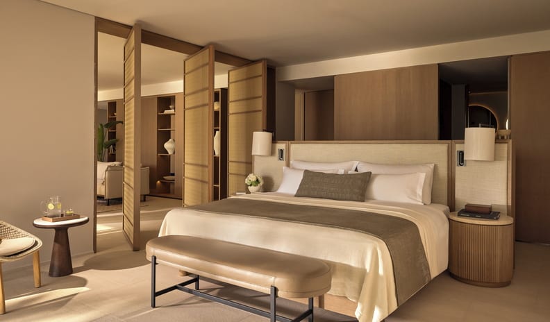 Two Bedroom Residence Pr. Pool Beach Front SV king-sized bed with neutral linens, a leather end bench, and elegant wooden folding partition doors at Sani Asterias by Kenwood Travel