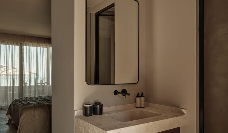 Classic bathroom interior with a natural stone sink, black-framed mirror, and contemporary minimalist styling at OKU Bodrum by Kenwood Travel