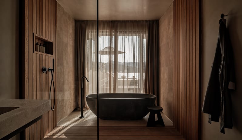 Deluxe Suite with Private Pool bathroom with a dark oval soaking tub, vertical wood slat walls, walk-in shower, and natural light at OKU Bodrum by Kenwood Travel