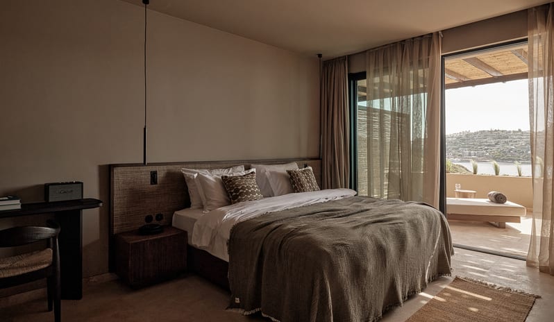 Junior Suite wabi-sabi style bedroom with textured olive green bedding, microcement walls, sleek pendant lighting, and a woven accent rug at OKU Bodrum by Kenwood Travel