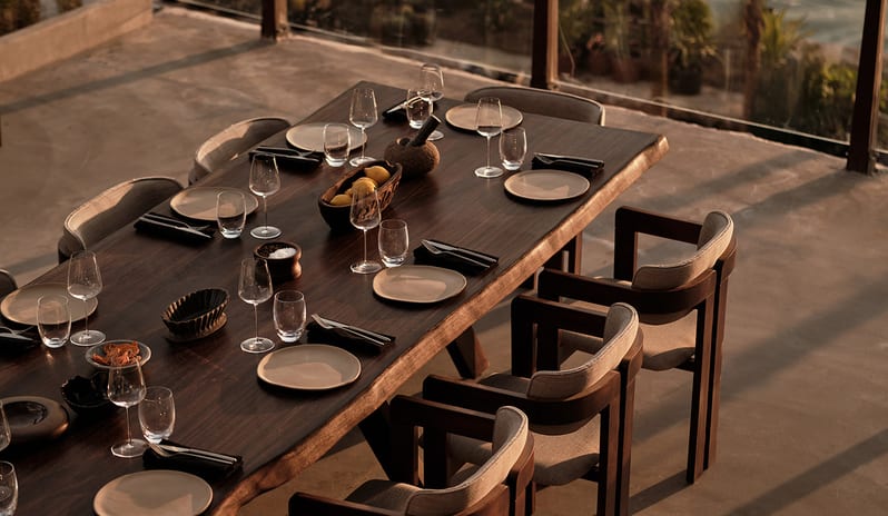 Teyo long dark wood dining table set for dinner on an outdoor terrace overlooking the sea at OKU Bodrum by Kenwood Travel