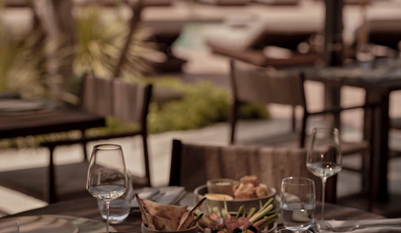 To Kima table filled with Mediterranean meze platters and wine glasses by a sunny beachside pool at OKU Bodrum by Kenwood Travel