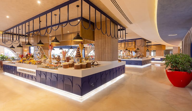 Turquoise Spacious and brightly lit upscale resort buffet restaurant showcasing dessert and fruit stations with a distinctive blue and wood architectural design at Rixos Radamis Sharm El Sheikh by Kenwood Travel