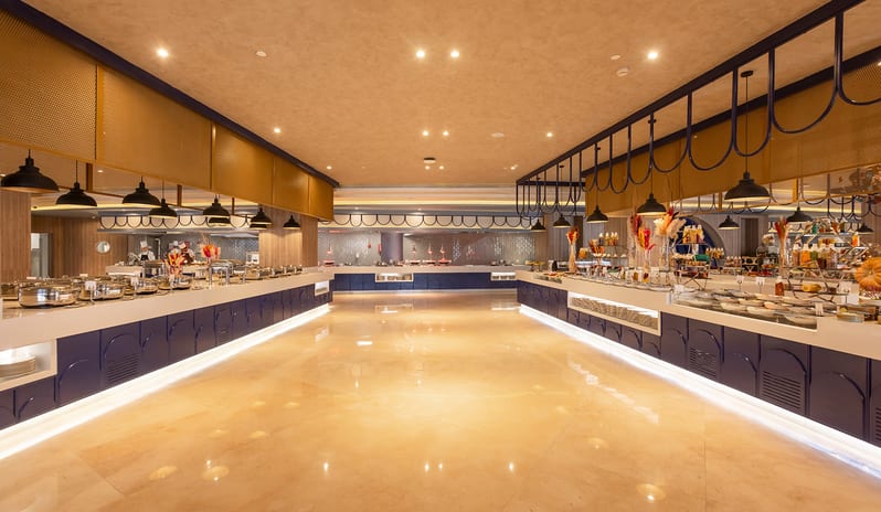 Turquoise Spacious and brightly lit upscale resort buffet restaurant showcasing dessert and fruit stations with a distinctive blue and wood architectural design at Rixos Radamis Sharm El Sheikh by Kenwood Travel