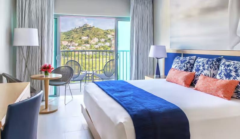 Mountain View Terrace King modern room decor, an indoor seating area, and a scenic balcony view of the hills at Harbor Club St. Lucia, Curio Collection by Hilton by Kenwood Travel