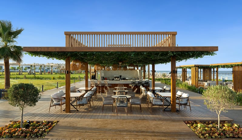 Beach Bar Outdoor beachfront lounge and bar area under a wooden pavilion draped in green vines at a luxury resort at Rixos Radamis Sharm El Sheikh by Kenwood Travel