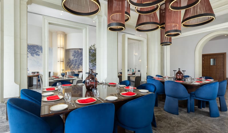 T-Bone Fine dining tables set with royal blue velvet chairs and distinctive overhead light fixtures at Rixos Radamis Sharm El Sheikh by Kenwood Travel