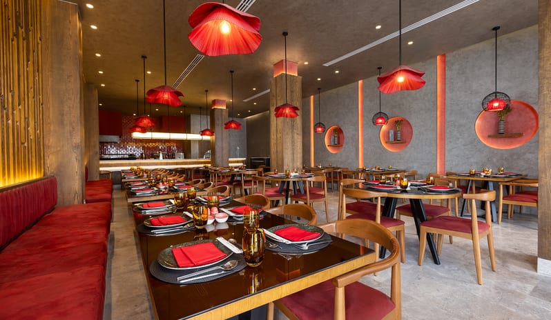 Wabi Sabi Modern Asian fine dining room with red velvet seating, concrete walls, and unique red pendant lighting at Rixos Radamis Sharm El Sheikh by Kenwood Travel