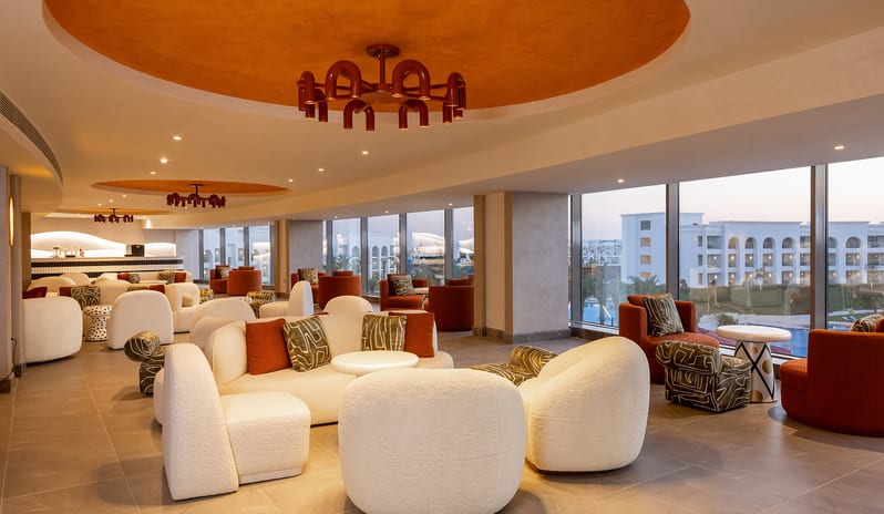 Candy Bar Modern resort lounge interior at Candy Bar with cream bouclé seating, orange accents, and panoramic windows at Rixos Radamis Sharm El Sheikh by Kenwood Travel