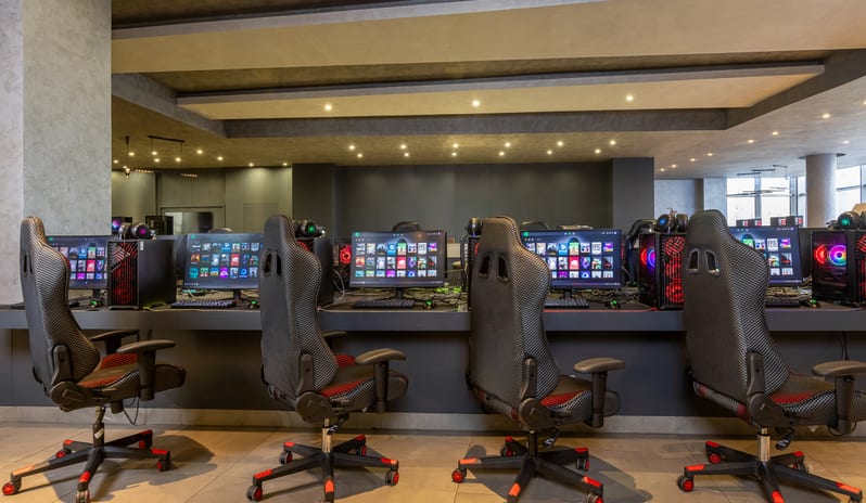 E-Sport Café Professional PC gaming stations with ergonomic chairs and illuminated computer towers at an esports cafe at Rixos Radamis Sharm El Sheikh by Kenwood Travel