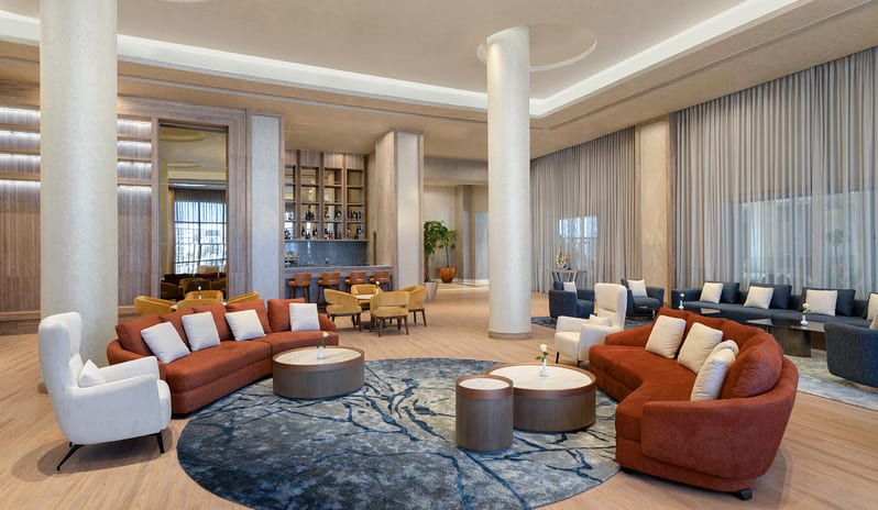 Executive Lounge Luxury hotel executive lounge interior featuring rust-orange sofas, modern armchairs, and a small service bar area at Rixos Radamis Sharm El Sheikh by Kenwood Travel