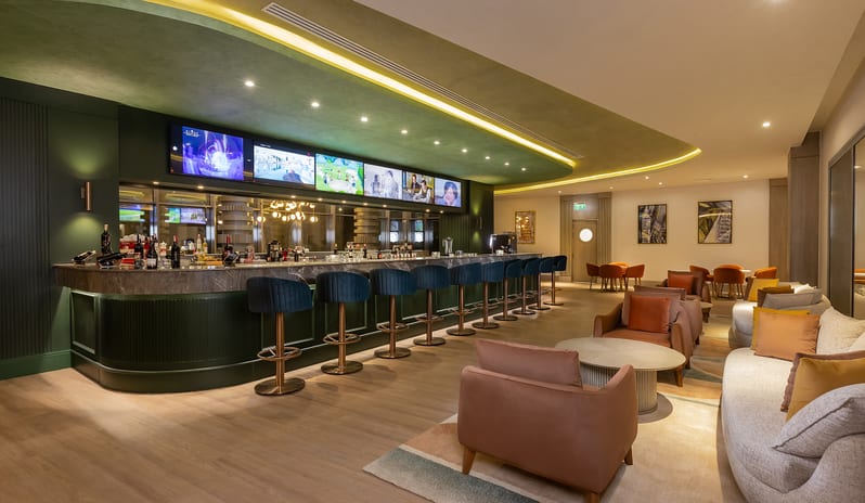 Irish Pub Modern sports bar and Irish pub interior showing a long counter with green stools, TV screens, and a lounge seating area at Rixos Radamis Sharm El Sheikh by Kenwood Travel