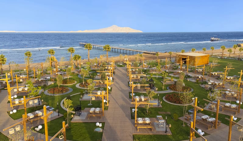 The Managal Elevated overview of The Mangal beachfront outdoor restaurant and its landscaped dining grounds at Rixos Radamis Sharm El Sheikh by Kenwood Travel