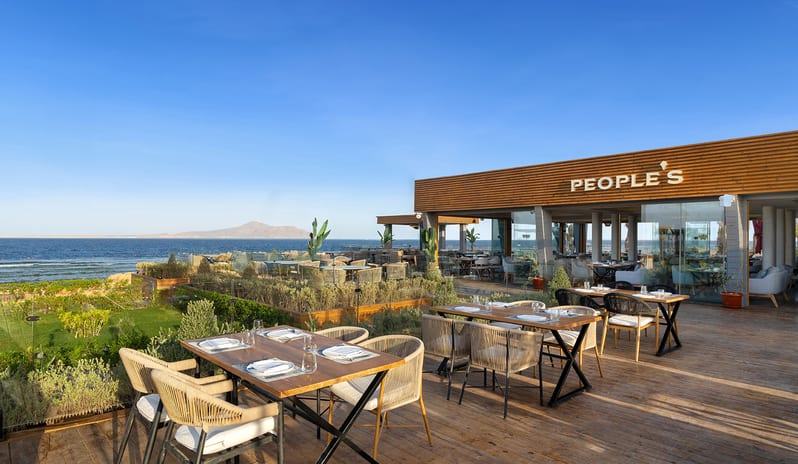 People's Restaurant Outdoor beachfront terrace dining tables and wooden deck seating at Rixos Radamis Sharm El Sheikh by Kenwood Travel