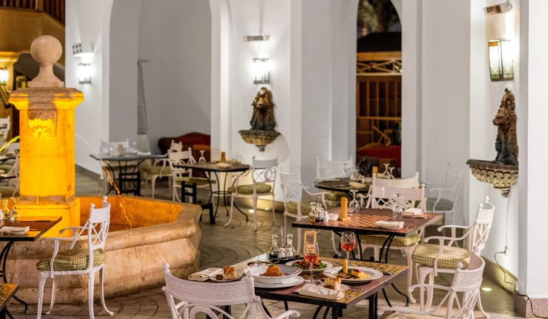 Rosmarino Gourmet dinner served on patio tables next to an illuminated stone water fountain in a luxury resort's outdoor courtyard restaurant at Savoy Sharm El Sheikh by Kenwood Travel