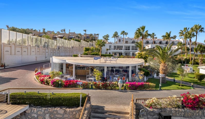 Viva Mar dining tables, surrounded by vibrant pink bougainvillea flowers and palm trees at Savoy Sharm El Sheikh by Kenwood Travel