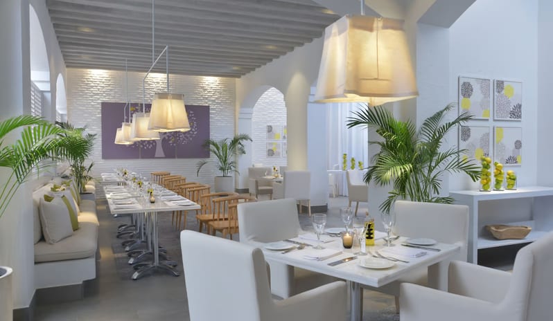 Limoni long banquet dining table, white leather chairs, and lemon-themed decor accents at Steigenberger Alcazar by Kenwood Travel