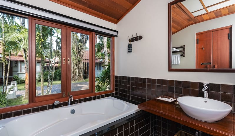 Oriental Villa bathroom interior with a bathtub next to a window at Khaolak Laguna Resort by Kenwood Travel