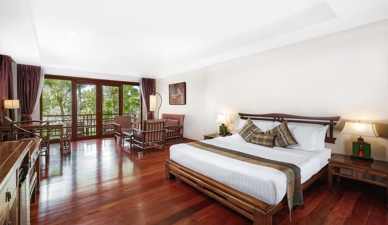 Siam Chaletat traditional wooden furniture and large windows opening to a tropical balcony at Khaolak Laguna Resort by Kenwood Travel