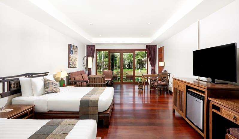 Siam Chaletat traditional wooden furniture and large windows opening to a tropical balcony at Khaolak Laguna Resort by Kenwood Travel