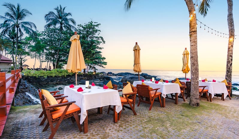 Sundowner Beachside Terrace open-air seaside dining tables by the beach at sunset at Khaolak Laguna Resort by Kenwood Travel